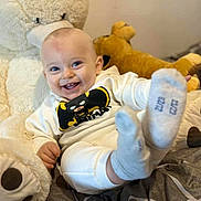 Ayden participe au concours pour gagner de l'argent avec cette photo : baby, smile, batman, plush_toy, stuffed_animal, socks, bed, clothing, child, happy, infant, cute, lying_down, soft_toy, face, person, indoors, playful, young_child, cozy