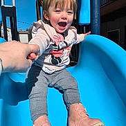 Izabell is registered to the contest to win money with this photo: toddler, child, slide, playground, boots, sweatshirt, pink, blue, hand_holding, smiling, happy, outdoor, daylight, person, clothing, fun, play, park, young_child, casual