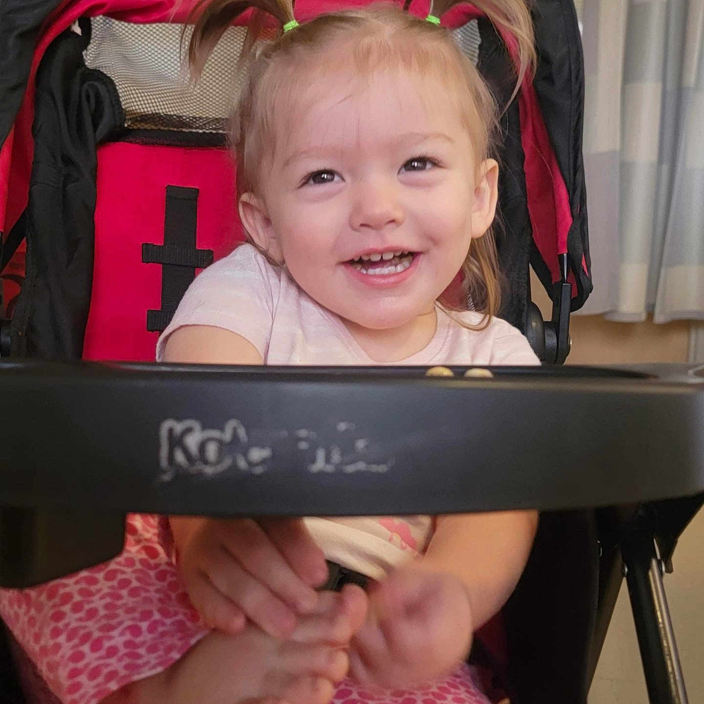 Izabell is registered to the contest to win money with this photo: baby, child, curtains, cute, face, feet, hair, hands, happy, indoor, joy, person, pigtails, pink_clothing, playful, seat, smiling, stroller, toddler, window