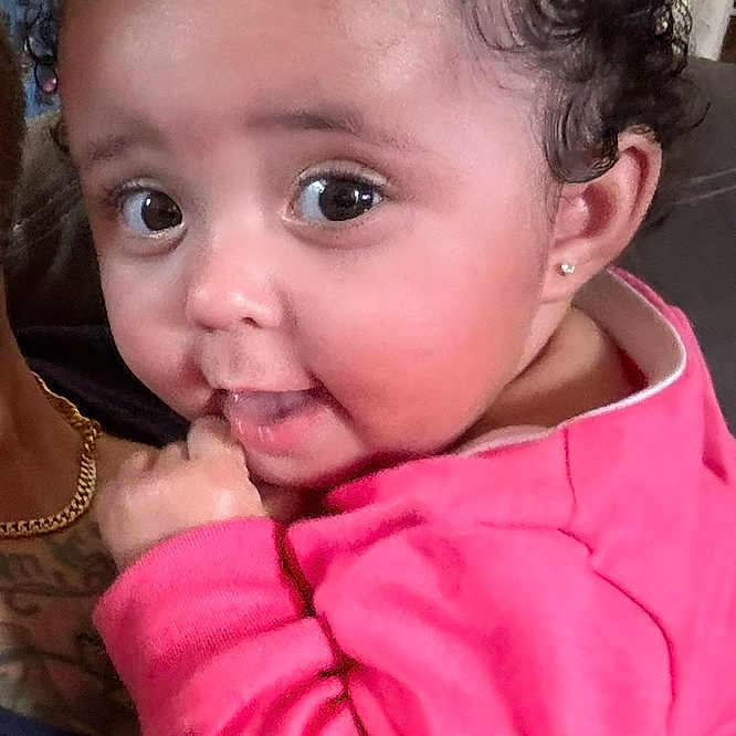 Nyrobi joined the competition — help win amazing prizes! baby, bow, child, couch, curly_hair, cute, earrings, eyes, face, hand, holding, home, indoor, infant, person, pink_clothing, portrait, skin, smiling, young