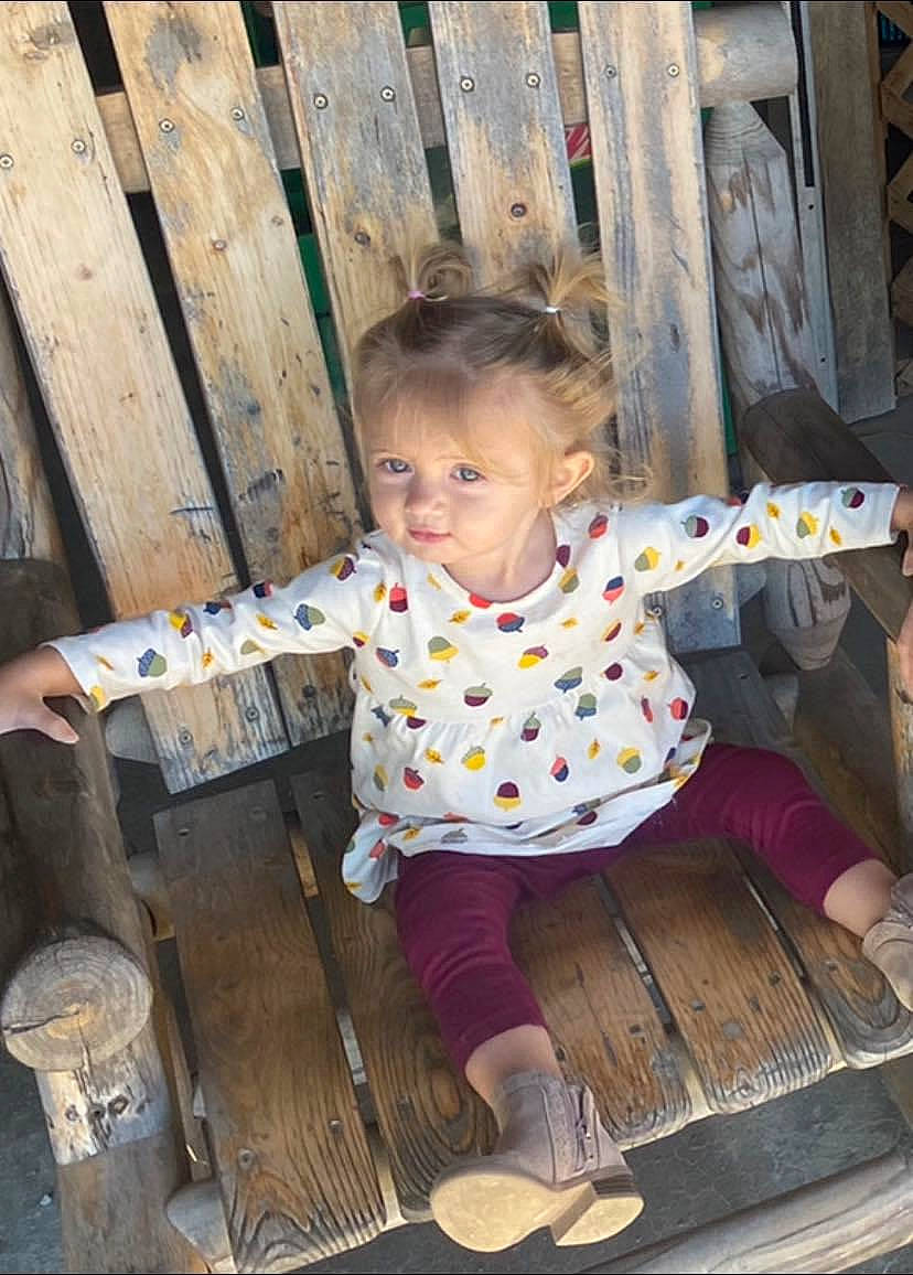 Kinslie is registered to the contest to win money with this photo: baby, baby_toddler_clothing, chair, child, fun, grass, happy, leisure, outdoor_bench, outdoor_furniture, pattern, person, play, product, recreation, sandal, sitting, toddler, vacation, wood