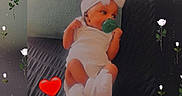 Maddison joined the competition — help win amazing prizes! baby, infant, pacifier, white_clothing, headband, pillow, bed, couch, indoor, decorative_overlay, flower_pattern, red_heart_emoji, cute, child, resting, small_person, face, hands, feet, soft_lighting
