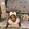 Maddison is registered to the contest to win money with this photo: baby, infant, pink, headband, bow, blanket, flower_petals, blocks, baby_blocks, floral, carpet, cute, portrait, child, indoors, soft_lighting, smiling, baby_girl, decor, tummy_time