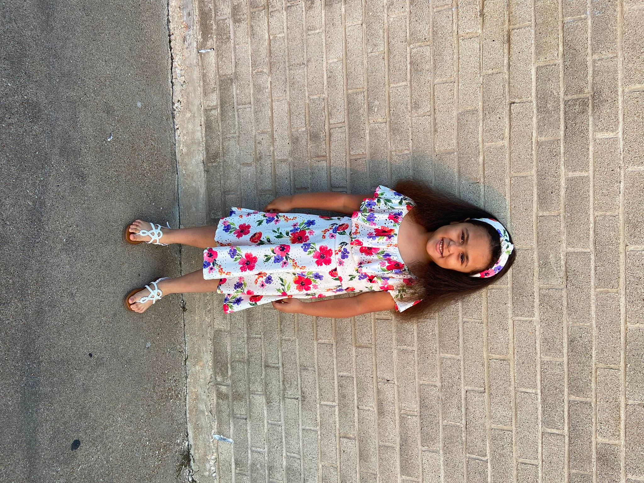 Tatum is registered to the contest to win money with this photo: baby_toddler_clothing, child, concrete, day_dress, dress, eyewear, flooring, foot, human_leg, joy, leisure, pattern, person, road_surface, sitting, sleeve, sunglasses, thigh, toddler, tree