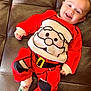 baby, child, smiling, red_clothing, santa_outfit, festive, couch, leather, socks, cute, happy, portrait, indoor, holiday, christmas, infant, person, cozy, playful, relaxed