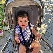 Thomas joined the competition — help win amazing prizes! toddler, child, stroller, baby, outdoor, sunlight, potted_plant, flowers, smiling, striped_clothing, curly_hair, seatbelt, pavement, greenery, happy, person, infant, baby_clothes, daylight, garden