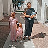 Essence is registered to the contest to win money with this photo: children, baby, mother, family, easter, outdoor, sunlight, walkway, residential, buildings, portrait, smiling, dresses, pink_clothing, braids, infant, sibling, sandals, trees, text_overlay
