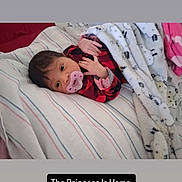 Essence joined the competition — help win amazing prizes! newborn, baby, infant, child, portrait, lying_down, pacifier, blanket, bed, bedding, striped_sheet, red_clothing, pink_clothing, sleeping_area, indoor, home, face, hands, baby_photo, text_overlay