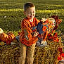 Braxton is registered to the contest to win money with this photo: child, boy, pumpkin_shirt, scarecrow, hay_bale, pumpkin, fall_leaves, autumn, outdoor, grass, smiling, toy, seasonal, festival, nature, daylight, casual_clothing, pants, shoes, decoration