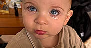 Lucas participe au concours pour gagner de l'argent avec cette photo : baby, beige_clothing, blue_eyes, bottle, child, close_up, collared_shirt, expression_sad, eyelashes, face, high_resolution, indoor, kitchen, looking_up, person, portrait, table, tear_stains, tears, toddler