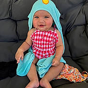Oaklynn is registered to the contest to win money with this photo: baby, child, smiling, towel, hood, red_checkered, clothing, sitting, cushion, chair, indoor, cute, happy, infant, person, skin, foot, hand, face, apparel