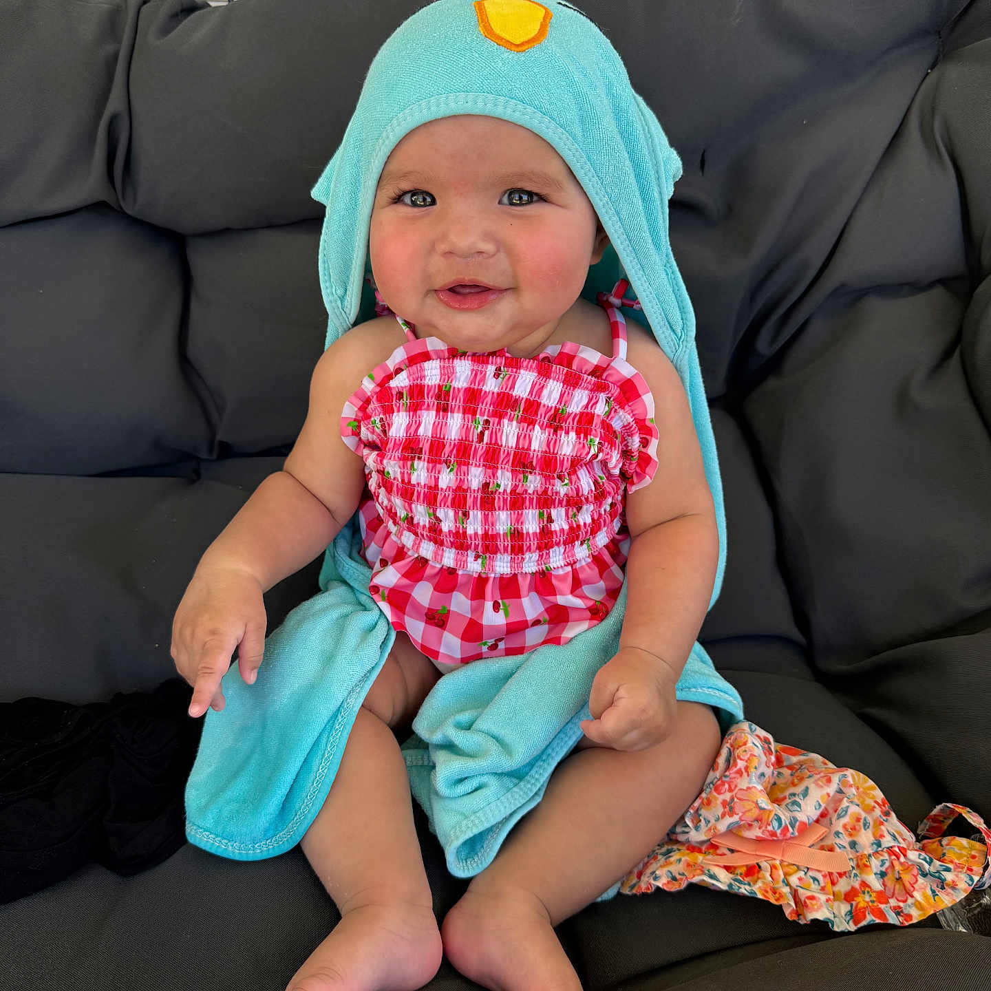 Oaklynn is registered to the contest to win money with this photo: baby, child, smiling, towel, hood, red_checkered, clothing, sitting, cushion, chair, indoor, cute, happy, infant, person, skin, foot, hand, face, apparel
