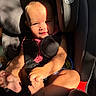 baby, child, car_seat, sunlight, shadow, face, feet, sitting, graco, seatbelt, infant, pink_clothing, curious, expression, indoor, safety, child_safety, person, closeup, portrait