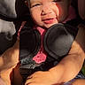 Oaklynn is registered to the contest to win money with this photo: baby, child, car_seat, sunlight, shadow, holding_foot, pink_clothing, harness, cute, infant, sitting, portrait, face, skin, expression, indoors, seat, safety, person, young