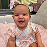 baby, child, smiling, floral_dress, pink_blanket, sitting, indoors, face, happy, cute, infant, person, home, soft_light, window_blinds, plush, arm, head, skin, furniture