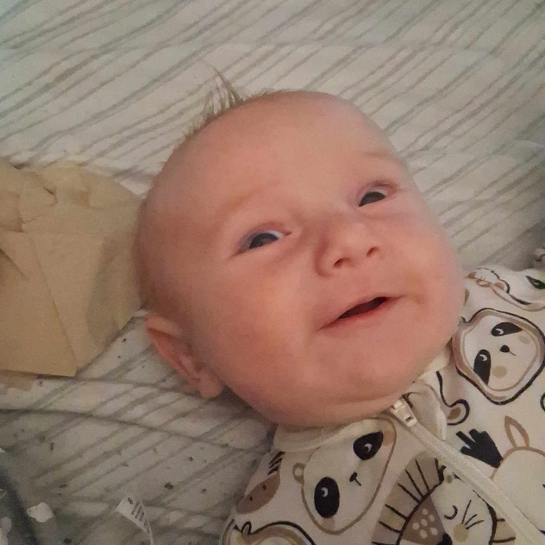 Leyland joined the competition — help win amazing prizes! baby, smiling, infant, bed, blanket, clothing, onesie, animal_print, face, head, happy, lying_down, indoors, cute, child, young, expression, portrait, sleepwear, soft