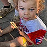 Daelen joined the competition — help win amazing prizes! child, toddler, curly_hair, blue_eyes, snack, messy_face, shirt, puerto_rican_flag, sitting, outdoor, concrete_floor, legs, shoes, casual, summer, daylight, portrait, cute, food, happy