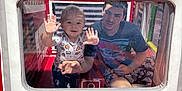 Daelen is registered to the contest to win money with this photo: toddler, child, young_man, play_area, indoor, window, transparent, hands, smile, curious, colorful, red, white, yellow, green, netting, shirt, patterned_pants, baby_yoda, fun