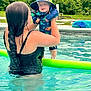 Henry joined the competition — help win amazing prizes! adult, baby, braid, child, dinosaur_print, fun, greenery, hat, holding, outdoor, parent, playful, pool_noodle, recreation, smile, summer, sunny, swimming_pool, swimsuit, water