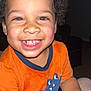 Ezariah is registered to the contest to win money with this photo: child, toddler, smiling, curly_hair, orange_shirt, dinosaur_graphic, indoor, portrait, happy, face, person, cute, baby, skin, hand, eyes, teeth, expression, young, fun