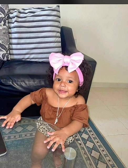 Adelyn is registered to the contest to win money with this photo: chair, chest, child, comfort, couch, eyelash, face, floor, flooring, happy, headband, headpiece, headwear, human_leg, joy, living_room, magenta, person, pink, purple