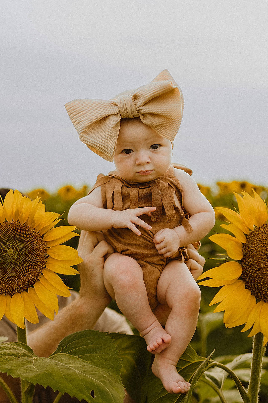 Lainey is registered to the contest to win money with this photo: baby, costume_hat, doll, facial_expression, fashion_accessory, flower, grass, grassland, happy, hat, headgear, headpiece, illustration, people_in_nature, person, petal, plant, sitting, sun_hat, toddler