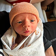 Branden joined the competition — help win amazing prizes! arm, baby, blanket, closeup, cute, expression, eyes, face, hat, holding, human, indoors, infant, knit_cap, newborn, person, skin, swaddle, tattoo, wrapped