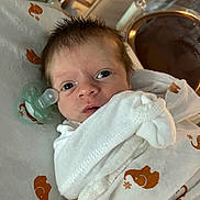 Branden is registered to the contest to win money with this photo: newborn, baby, infant, swaddle, blanket, pacifier, hospital, bed, face, eyes, hair, person, cute, sleepwear, rest, small, child, indoors, portrait, comfort