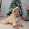 David is registered to the contest to win money with this photo: baby, child, crawling, reindeer_onesie, holiday, christmas_tree, decorations, indoor, smiling, happy, festive, floor, toy, cute, infant, holiday_lights, seasonal, warm_clothing, joyful, portrait