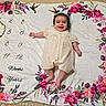 baby, infant, child, smiling, portrait, lying_down, milestone_blanket, floral, flowers, hummingbird, cream_dress, bow, indoor, blanket, textile, photography, happy, face, family_photo, milestone