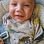 baby, child, smiling, dinosaur_pattern, onesie, car_seat, seatbelt, infant, cute, happy, face, clothing, straps, head, person, closeup, indoor, young, comfort, safety
