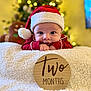 baby, infant, christmas, holiday, santa_hat, red_clothing, blanket, wooden_sign, two_months, decorations, gingerbread_man, christmas_tree, indoors, portrait, cute, smiling, festive, holiday_decor, child, person