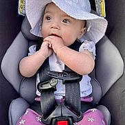 Olivia joined the competition — help win amazing prizes! baby, infant, child, car_seat, sunhat, floppy_hat, harness, portrait, sitting, wide_eyed, facial_expression, hands, floral_clothing, purple_pants, vehicle, interior, safety_buckle, close_up, photography, adorable