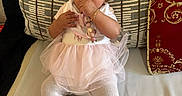 Lylah is registered to the contest to win money with this photo: baby, bracelet, child, clothing, couch, cushion, cute, decor, headband, indoor, infant, patterned_cushion, person, pink_bow, pink_shoes, portrait, sitting, thumb_sucking, tutu, white_tights