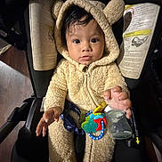 Xander joined the competition — help win amazing prizes! baby, child, car_seat, onesie, fuzzy_clothing, toy, bottle, indoor, cute, expression, infant, curious, seatbelt, portrait, young_child, face, hand, dark_background, cozy, hood