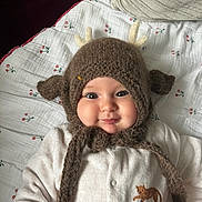 Marguerite a rejoint le concours — aidez-le/la à gagner de superbes lots ! baby, infant, smile, cheeks, knitted_hat, antlers, blanket, onesie, cat_patch, pillow, toy, indoor, portrait, close_up, cute, eyes, face, soft_texture, cozy, baby_clothing