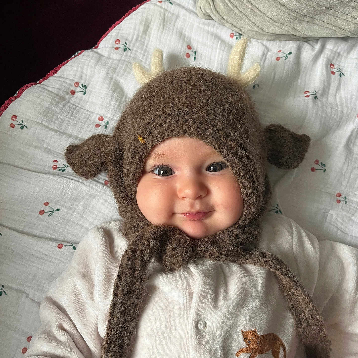 Marguerite a rejoint le concours — aidez-le/la à gagner de superbes lots ! antlers, baby, baby_clothing, blanket, cat_patch, cheeks, close_up, cozy, cute, eyes, face, indoor, infant, knitted_hat, onesie, pillow, portrait, smile, soft_texture, toy