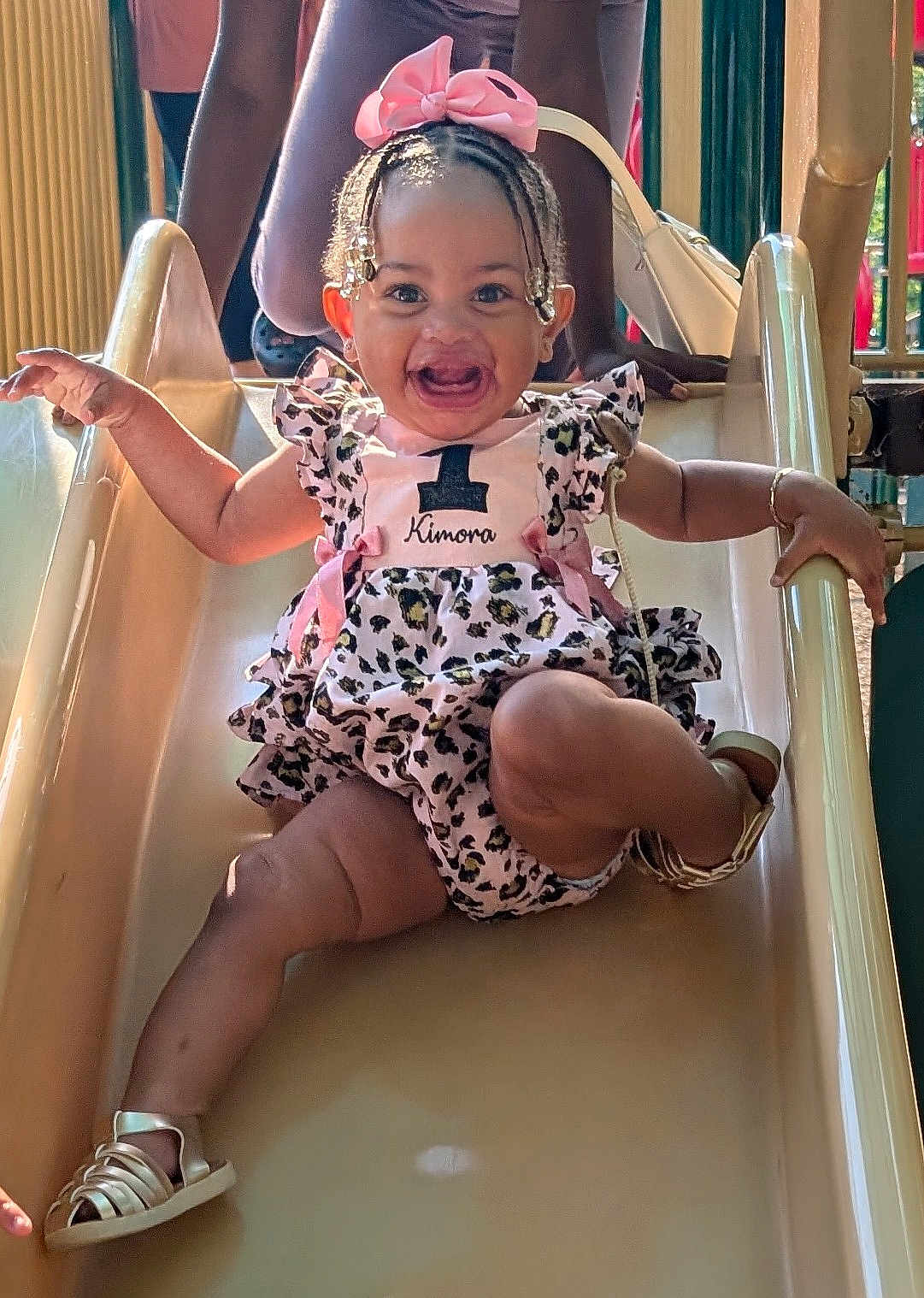 Kimora joined the competition — help win amazing prizes! baby, child, slide, playground, smiling, happy, dress, bow, braids, sandals, outdoor, person, fun, cute, joy, summer, park, ramp, leisure, activity