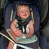 baby, blue_eyes, car, car_interior, car_seat, child, clothing, cute, fabric, hands, happy, infant, legs, person, safety, seatbelt, sitting, smile, soft_book, young