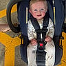 Atlas is registered to the contest to win money with this photo: baby, car_seat, child, onesie, animal_print, floor, yellow_lines, concrete, feet, slippers, straps, smile, blue, infant, sitting, person, cute, indoor, clothing, happy