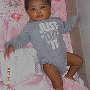 Ava is registered to the contest to win money with this photo: animal_pattern, baby, blanket, child, clothing, curly_hair, cute, elephant, face, indoors, infant, legs, lion, onesie, pacifier, pink, sleeping_area, soft_toys, toddler, zebra