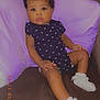 Ava is registered to the contest to win money with this photo: baby, brown_furniture, child, couch, cozy, curly_hair, cute, heart_pattern, indoor, infant, knitted_booties, looking_at_camera, onesie, portrait, purple_cushion, relaxed, sitting, small_hands, soft_lighting, white_socks