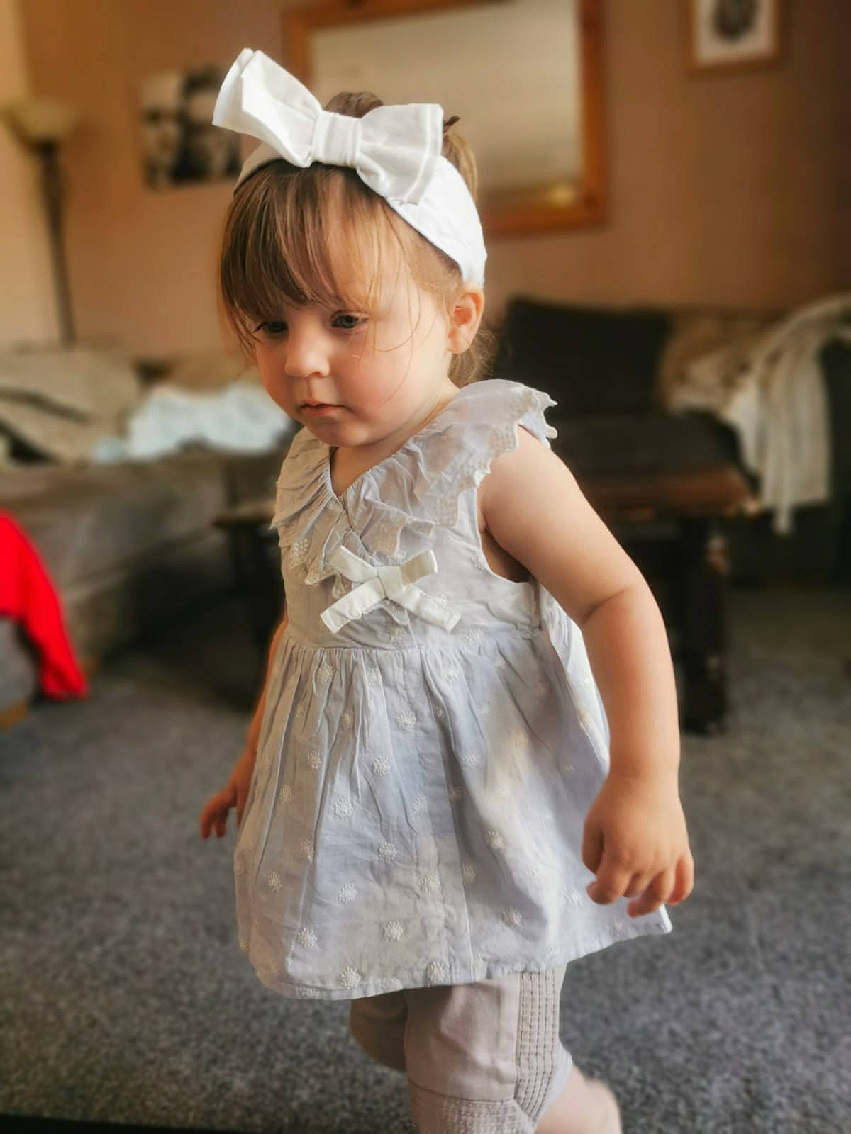 Orla is registered to the contest to win money with this photo: arm, baby_toddler_clothing, dress, eye, flash_photography, floor, flooring, fun, hair, happy, head, headgear, human_body, long_hair, one_piece_garment, person, petal, shoulder, skin, toddler