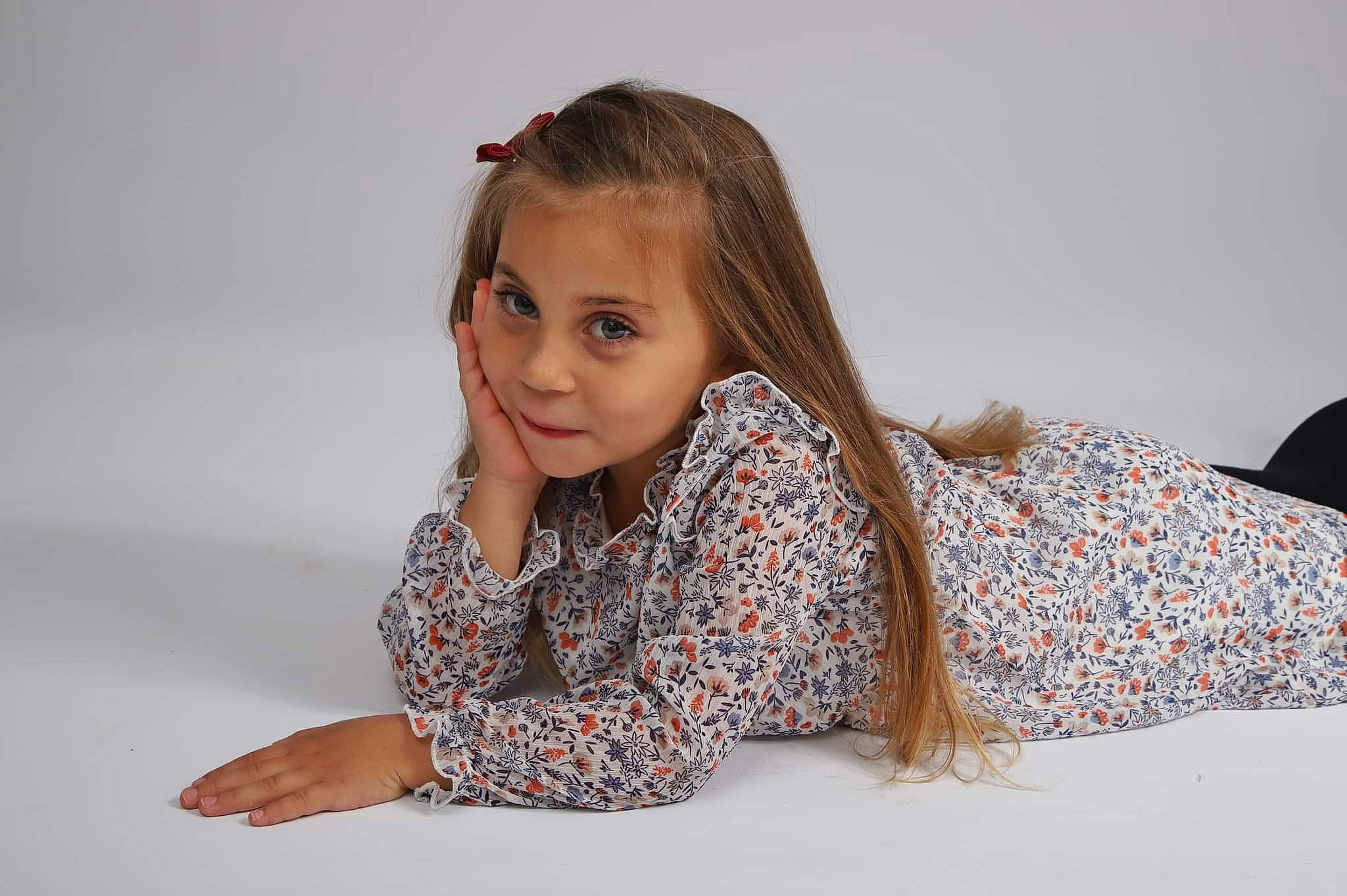 Isya a rejoint le concours — aidez-le/la à gagner de superbes lots ! arm, comfort, dress, elbow, eye, fashion_design, flooring, gesture, happy, human_leg, long_hair, neck, pattern, person, sitting, sleeve, smile, t_shirt, thigh, toddler