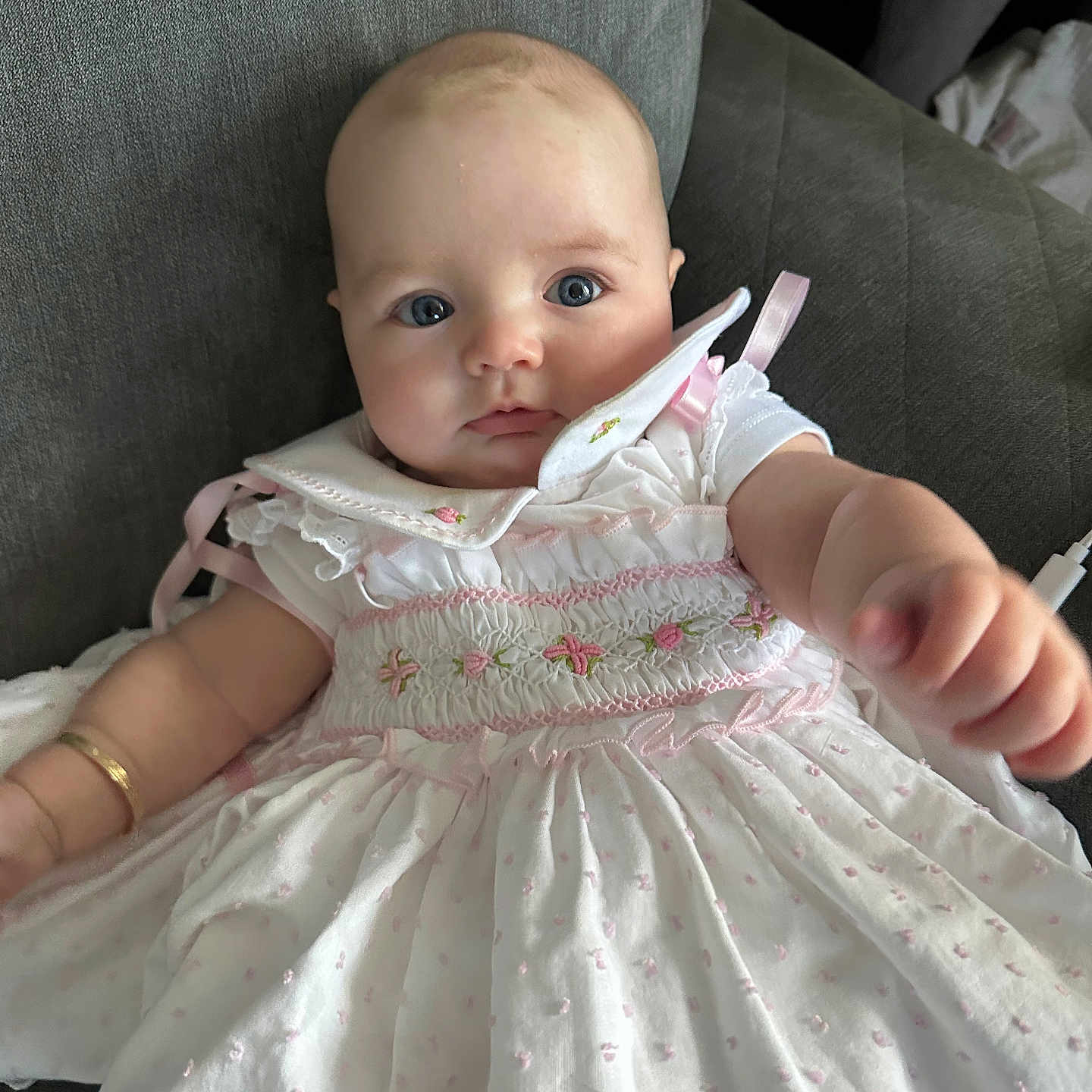 Neiri-Leigh joined the competition — help win amazing prizes! adorable, baby, blue_eyes, child, close_up, couch, cute, dress, face, furniture, indoor, infant, person, pink_embroidery, portrait, reaching_hand, sitting, soft_lighting, white_dress, young_child