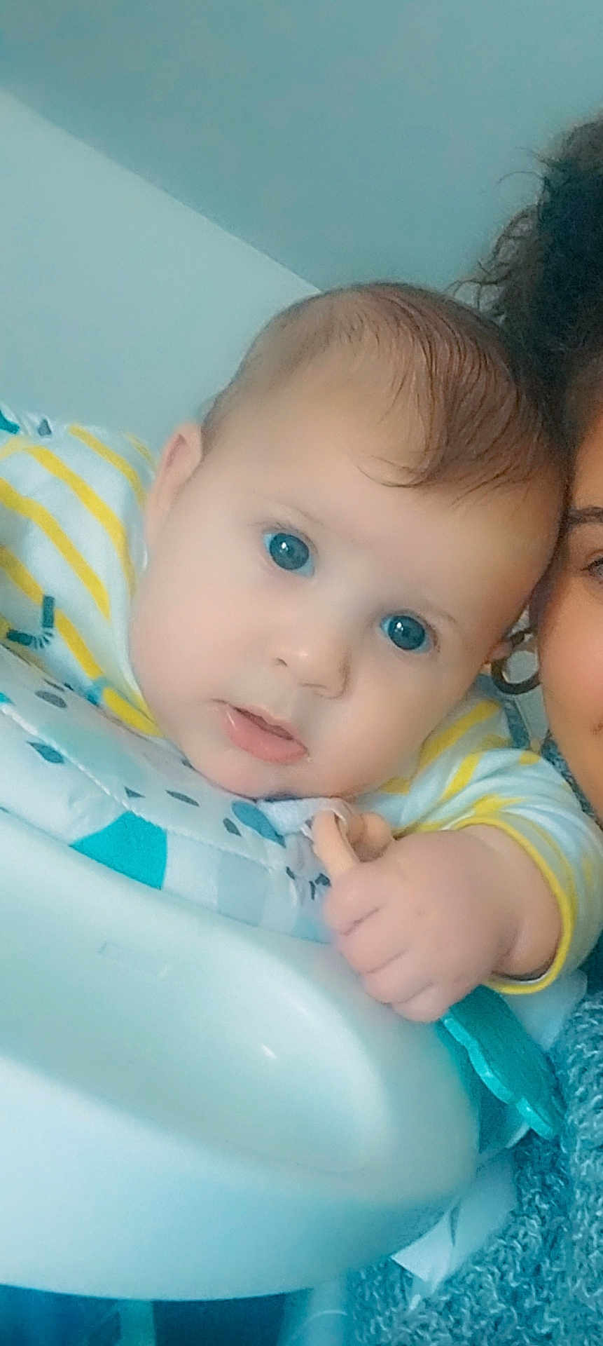 Kaïs participe au concours pour gagner de l'argent avec cette photo : adult, baby, blue_eyes, child, closeup, clothing, curious, face, hair, hand, head, high_chair, indoor, infant, partial_face, person, skin, smile, striped_shirt, toy