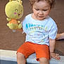 child, toddler, curly_hair, plush_toy, yellow_bunny, nirvana_tshirt, orange_shorts, white_sneakers, sitting, indoor, carpeted_floor, step, cute, casual_clothing, playful, person, young_child, holding_toy, smiling_toy, relaxed