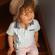 Rayan participe au concours pour gagner de l'argent avec cette photo : toddler, child, curly_hair, hat, smiling, stairs, pacifier, clothing, shorts, shirt, footwear, indoors, wood, happy, person, baby, casual, cute, sitting, accessory