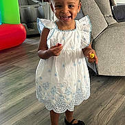 Maliyah joined the competition — help win amazing prizes! child, toddler, smiling, dress, indoor, wooden_floor, living_room, furniture, happy, person, footwear, black_shoes, toy, playful, home, cute, girl, flooring, portrait, young_child