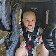 Dominic is registered to the contest to win money with this photo: baby, child, car_seat, evenflo, smiling, happy, straps, seatbelt, infant, outdoor, sunlight, fan, clothing, sitting, safety, cute, person, face, head, legs